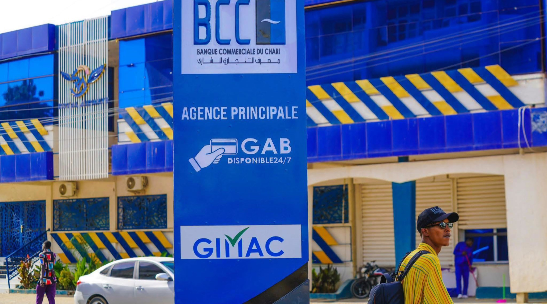 Commerçante tchadienne consultant son téléphone devant son étal de tissus à N'Djamena